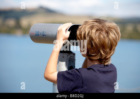 Child 8 looking through public telescope at lake taupo new zealand Stock Photo
