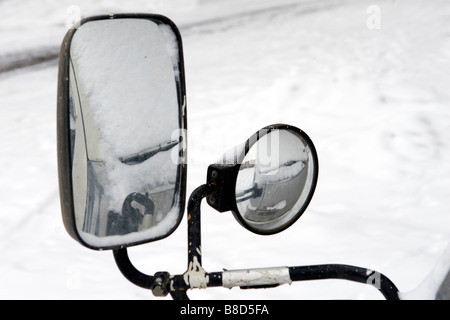 Two sidemirrors covered with snow over winter road. Stock Photo