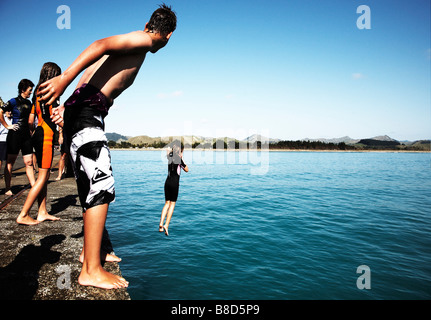 children 14 jumping of wharf into sea Stock Photo