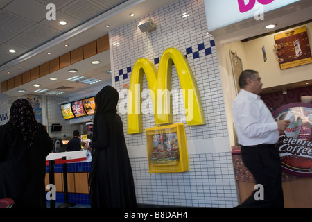 Two muslim women in their abayas leave a McDonalds fast food restaurant Stock Photo