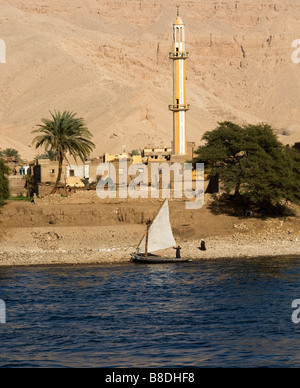 Felucca in River Nile with houses and mosque on river side. Stock Photo