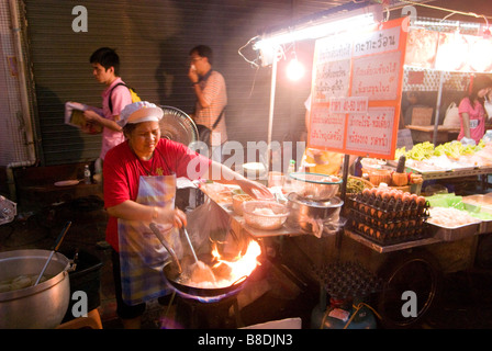 Woman cooking stir fry Thai Chinese food on a night market Thanon Yaowarat road in Chinatown central Bangkok Thailand Stock Photo