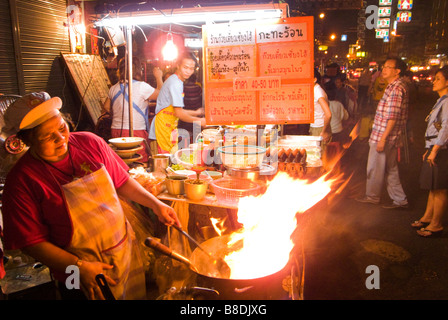 Woman cooking stir fry Thai Chinese food on a night market Thanon Yaowarat road in Chinatown central Bangkok Thailand Stock Photo