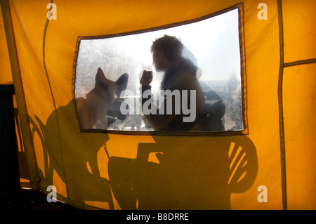 A man and his dog behind a windscreen at a cafe on Brighton Beach, UK Stock Photo