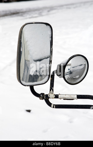 Two sidemirrors covered with snow over winter road. Stock Photo