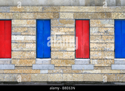 Four closed metal window shutters over stone covered wall. Stock Photo