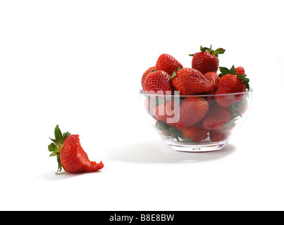 Bowl of Red Strawberries with one eaten in foreground Stock Photo