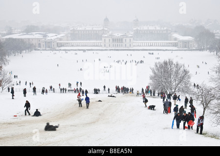 People in Greenwich Park enjoy a heavy snowfall building snowmen and sledging. Stock Photo