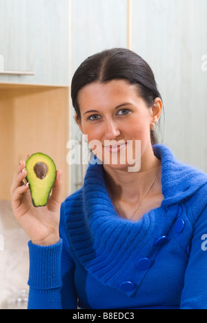 Beautiful young woman holding a halved avocado fruit Stock Photo