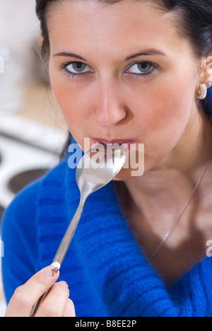 Woman licking a spoon Stock Photo