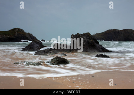waves wrapping around large rocks on beach. Stock Photo