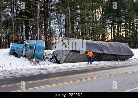 Semi truck in ditch in snow with a man looking on Stock Photo