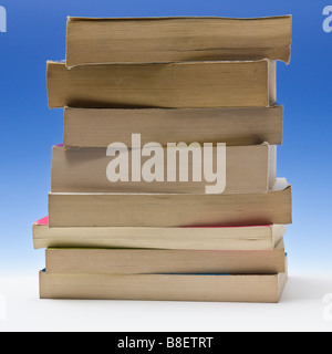 Stack of paperback books on a blue studio background. Stock Photo