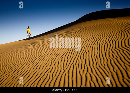 Woman wearing shorts standing on sand dune with ripple marks Maspalomas Gran Canaria Spain Stock Photo