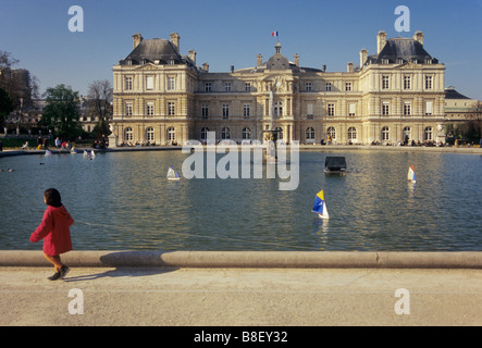 Child at The Octagonal Lake at Luxembourg Gardens with Luxembourg Palace seat of French Senate in distance Paris France Stock Photo