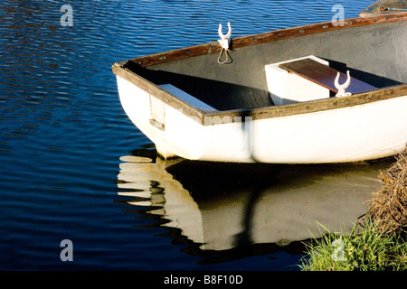 Moored white rowing boat reflected in water Stock Photo