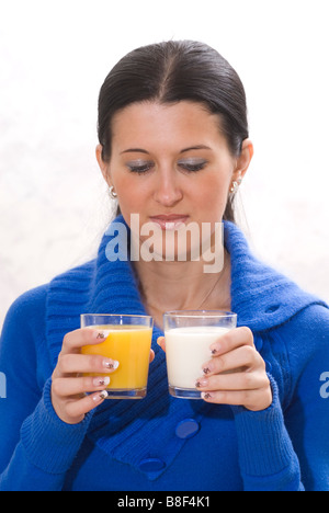 Young woman choosing between orange juice and milk Stock Photo