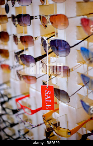Red Sale sign hanging from a pair of sunglasses among rows of sunglasses close up Stock Photo