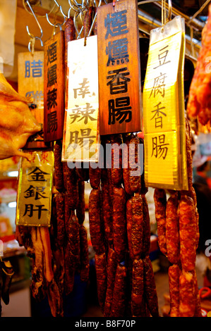 Preserved meat sausages with signs hanging from hooks on display in a market stall Stock Photo