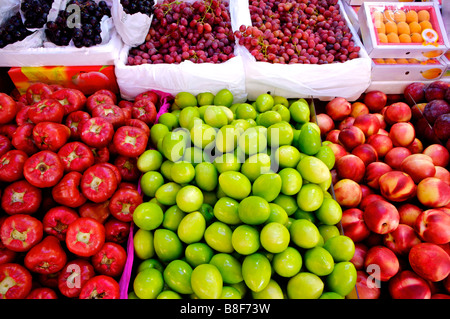 Fresh fruit including green dates wax apples peaches loquats and grapes on display in boxes in a market stall Stock Photo