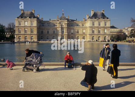 People at The Octagonal Lake at Luxembourg Gardens with Luxembourg Palace seat of French Senate in distance Paris France Stock Photo