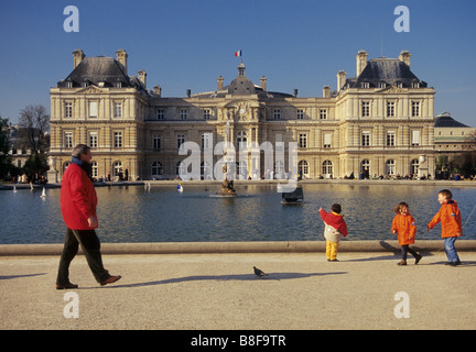 Children playing at The Octagonal Lake in Luxembourg Gardens with Luxembourg Palace seat of French Senate in dist Paris France Stock Photo