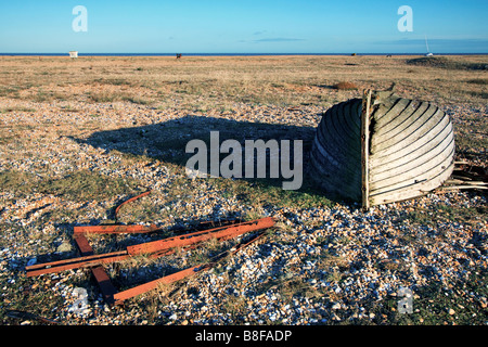 Old rusty street sign pointing to a derelict rowing boat on Dungeness beach Stock Photo