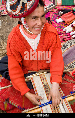 An Andean woman sits on the ground weaving alpaca wool into various products. Patacancha Valley, Peru. Stock Photo