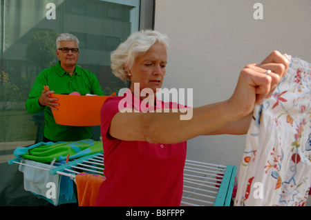 Senior man helping a senior woman hanging laundry on a line Stock Photo