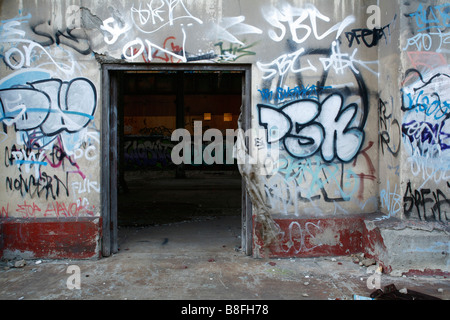 doorway on the wall of an abandoned old factory with heavy graffiti Stock Photo