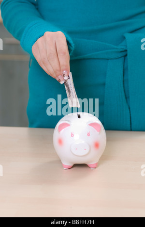 Close up of a woman saving money in a piggy bank Stock Photo