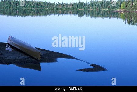 Scenic canoe overturned on shoreline rock Stock Photo