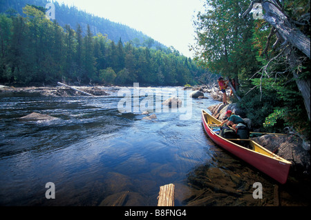 Unloading canoe above rapids in river Stock Photo