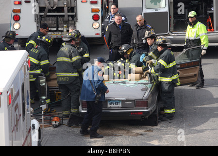 Firefighters extricate a woman from a Jaguar auto after cutting the roof off following a crash with a tractor trailer. Stock Photo
