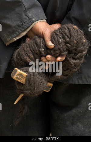 Tibetan man's hands - holding raw wool and spinning device. Sakya, Tibet Stock Photo