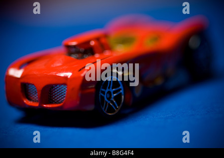 A red toy sports car against a blue background. Stock Photo