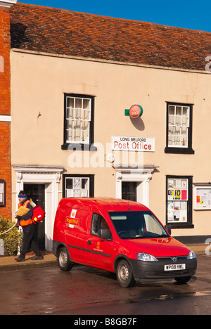 The post office with royal mail van and postman on his delivery round in the foreground at Long Melford,Suffolk,Uk Stock Photo
