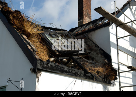 Burnt out roof and dormer window following thatched roof fire on farmhouse cottage Stock Photo