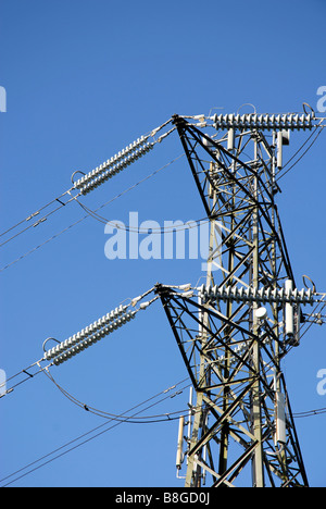 Top of electricity tower carrying high-tension cables, against cloudless blue sky Stock Photo
