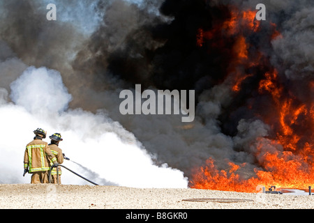 Firefighters using fire retardant foam to put out a jet fuel fire at an airport training facility in Boise Idaho USA Stock Photo