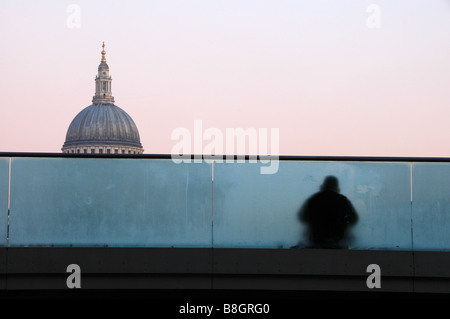 A homeless man sitting on Millenium Bridge, St. Paul's Cathedral dome in the background, London, England, UK Stock Photo