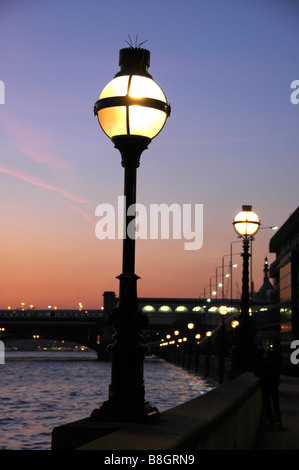 An ornate lamp against a sunset sky on Victoria Embankment with Blackfriars Bridge in the background, London, England, UK Stock Photo