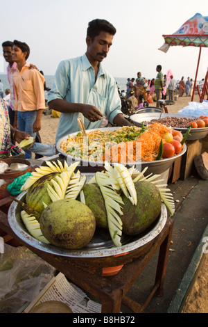 India Pondicherry Indian tourists relaxing on seafront promenade in late afternoon buying mango slices Stock Photo