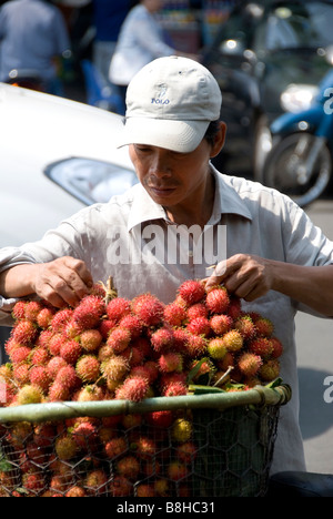 Man selling Rambutans in Saigon, Ho Chi Minh City, Vietnam Stock Photo
