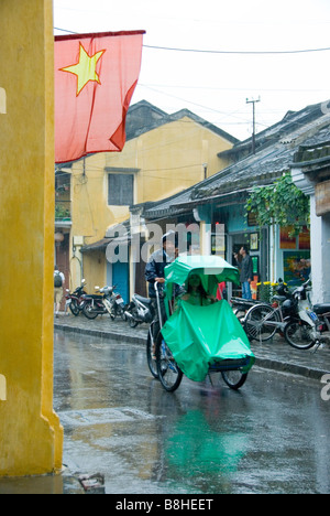 Cycling through the rain, Hoi An Vietnam Stock Photo