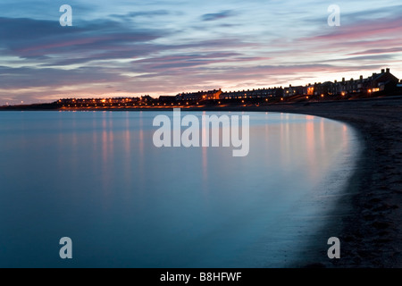 The sweep of the bay at Newbiggin by the Sea reflecting the colours of a late winter sunset Northumberland England Stock Photo