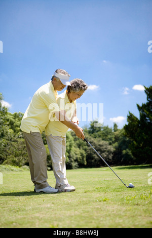 Senior man teaching his wife how to playing golf Stock Photo