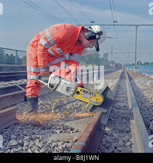 Contractor using abrasive disc machine cuts lengths of worn-out rail to be replaced during a trackwork upgrading programme. Stock Photo