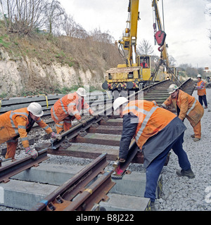 Contractors using rail crane lift redundant wooden-sleepered track panel before replacing with modern concrete equivalent. Stock Photo