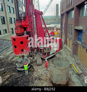 Rorary boring rig working in a confined city location excavating reinforced concrete foundation piles for a new river bridge. Stock Photo